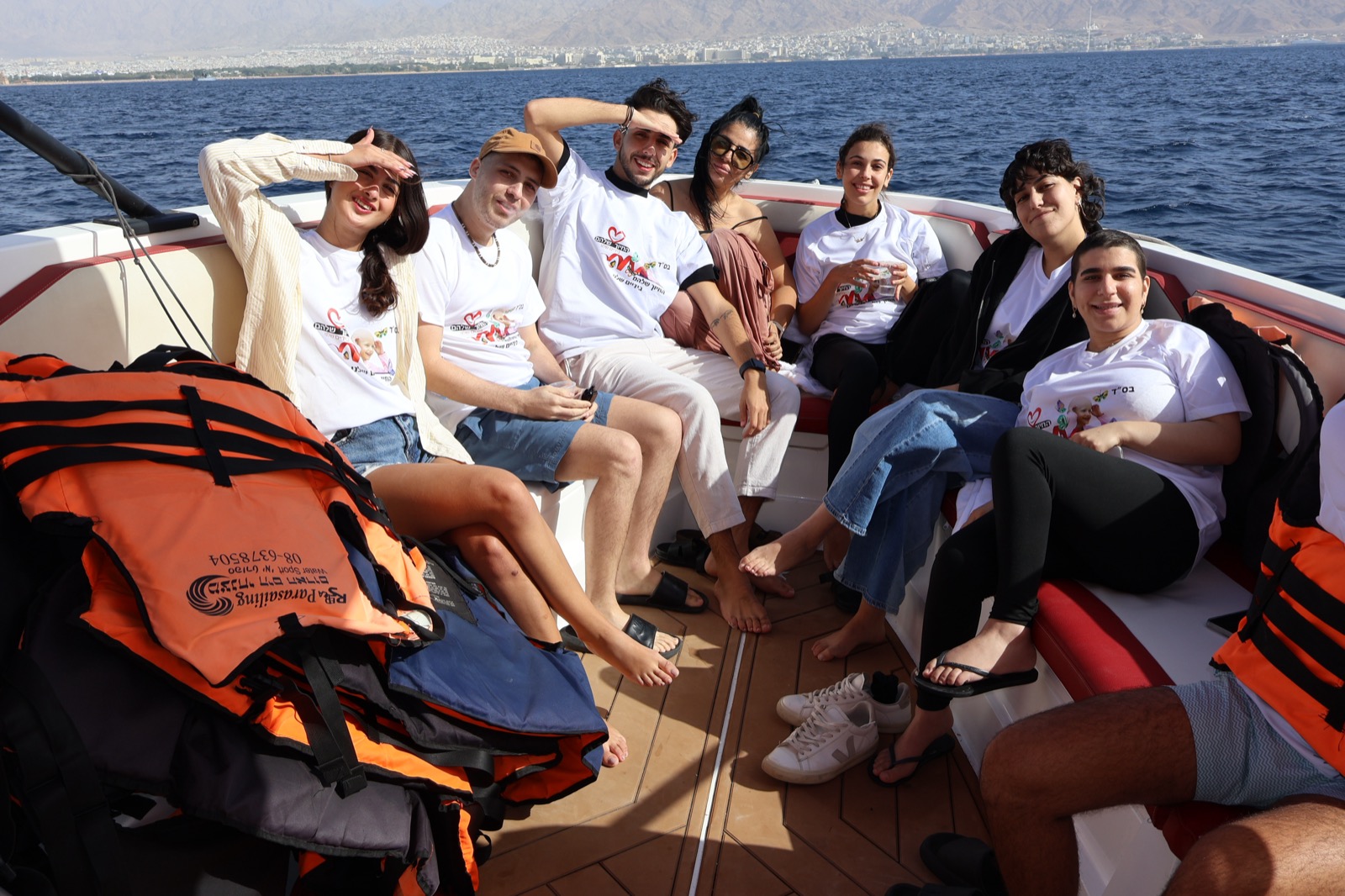 קבוצת מתנדבים ונתמכים מחייכים יחד בחולצות עמותה על ספינה