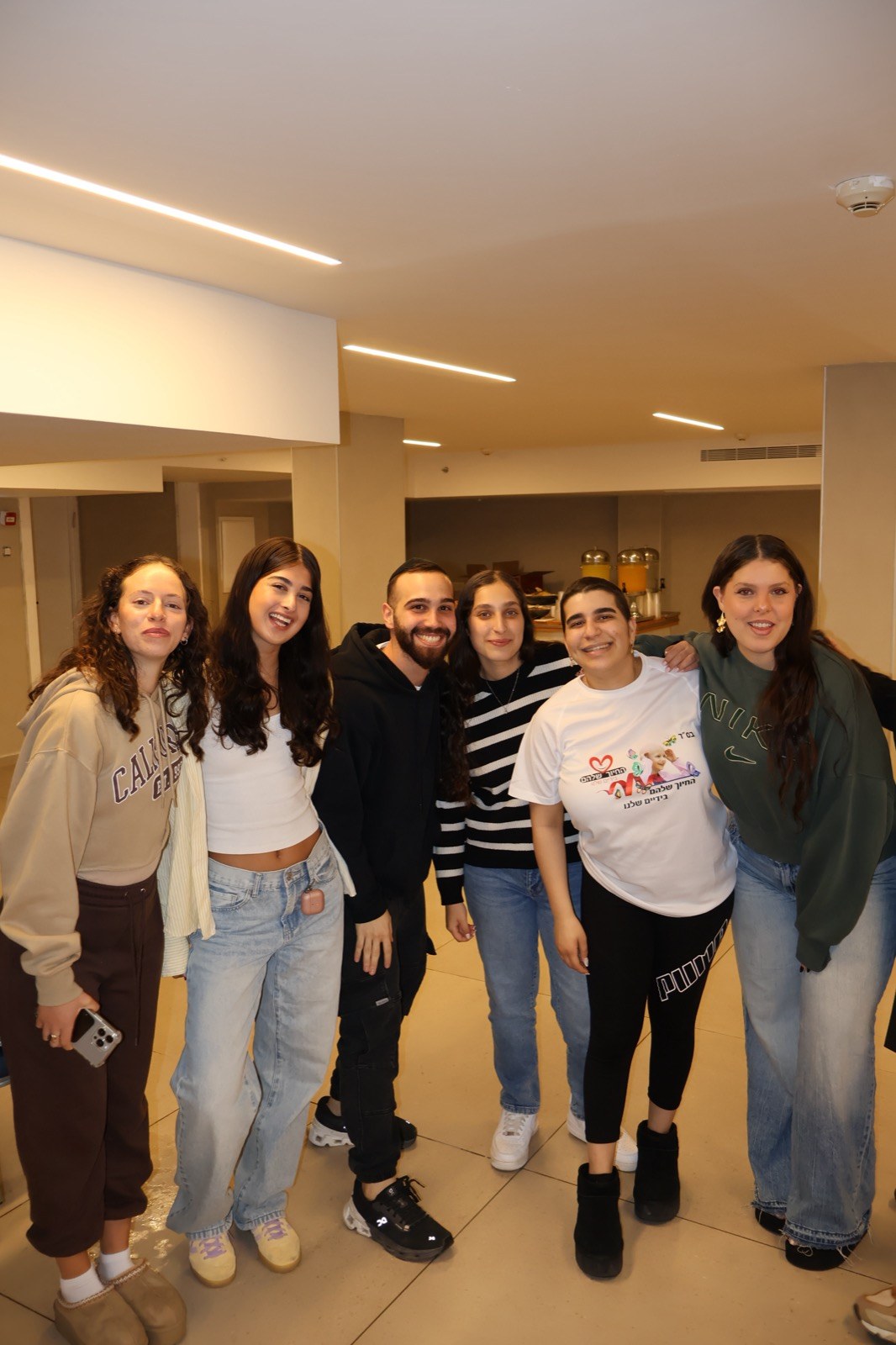 חמישה מתנדבים ונתמכים מחויכים בחולצות ארגון